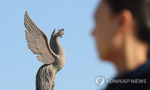 봉황 조형물 바라보는 관광객