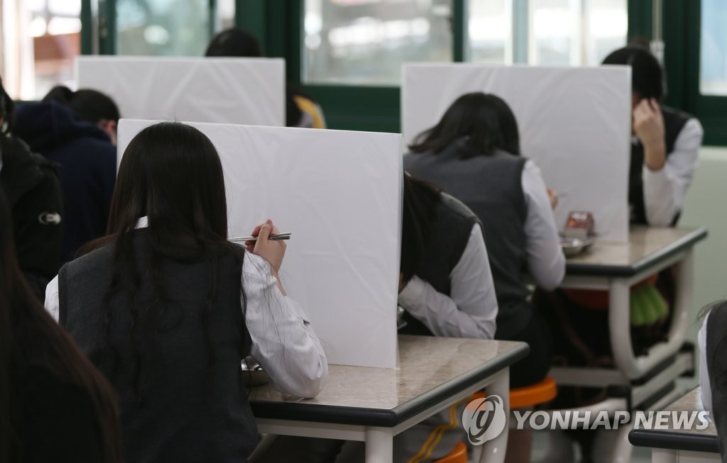칸막이 보며 식사하는 학생들