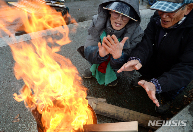 시장 골목에 찾아온 추위에 모닥불 쬐는 상인들