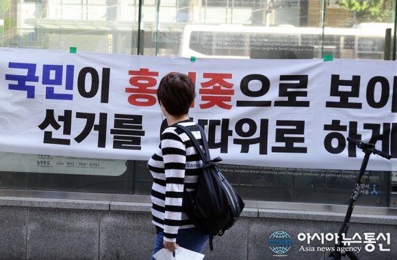 한글날 집회, 시위 현수막을 지나가는 시민이 바라보고  있다.